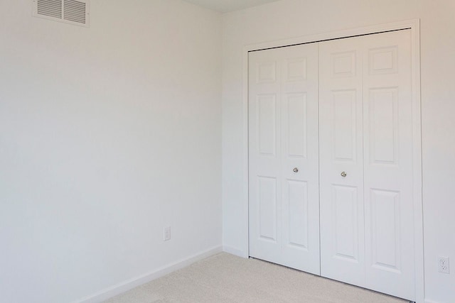 unfurnished bedroom with light carpet and a closet