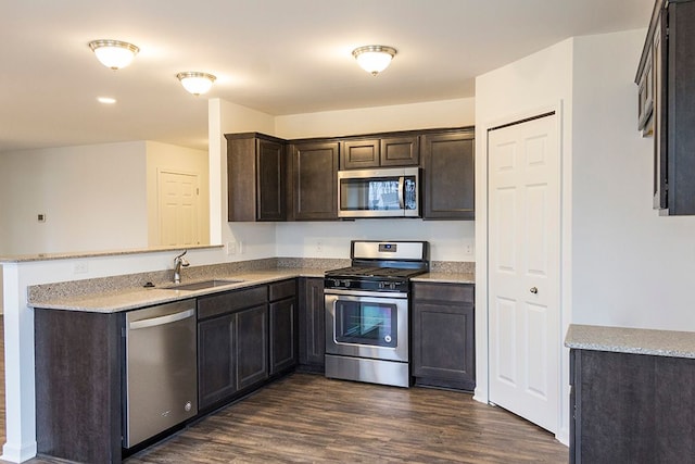 kitchen with dark wood-type flooring, sink, dark brown cabinets, light stone counters, and stainless steel appliances