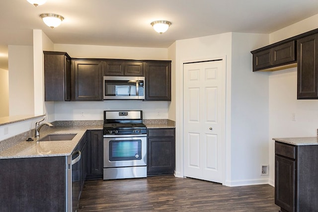 kitchen with dark brown cabinetry, sink, stainless steel appliances, light stone counters, and dark hardwood / wood-style floors