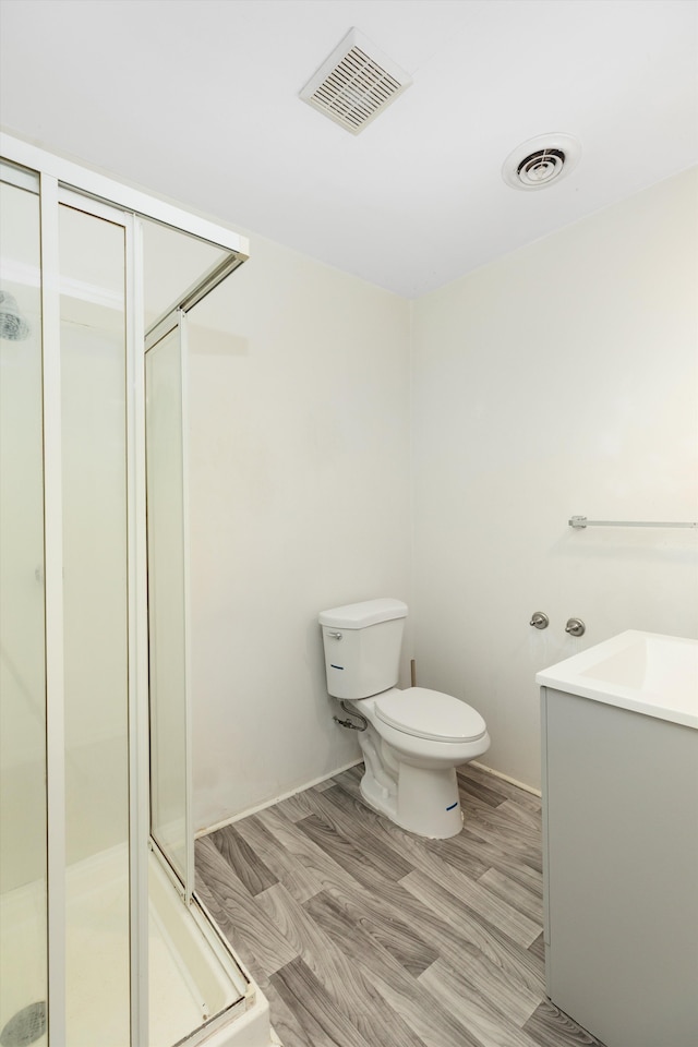 bathroom with vanity, hardwood / wood-style flooring, toilet, and an enclosed shower