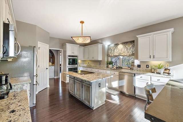 kitchen with dark wood-style floors, light stone countertops, a sink, stainless steel appliances, and white cabinets