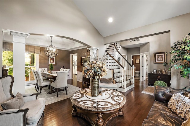 living room featuring a chandelier, dark hardwood / wood-style flooring, high vaulted ceiling, and ornate columns