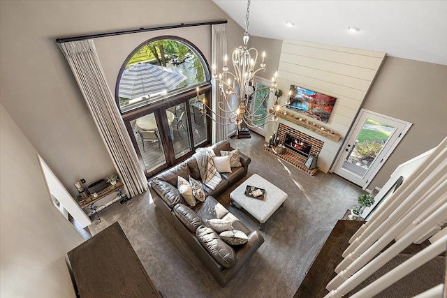 living room featuring carpet floors, an inviting chandelier, a towering ceiling, and a brick fireplace