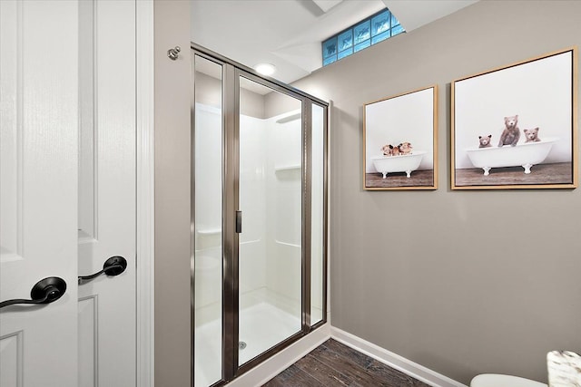 bathroom with baseboards, toilet, wood finished floors, and a shower stall