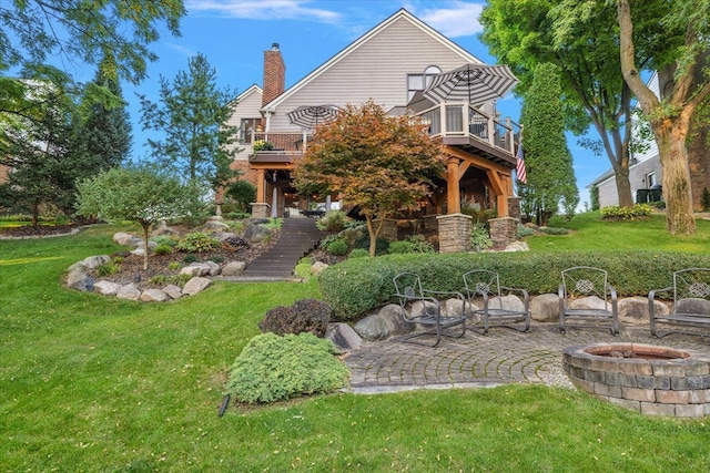 exterior space featuring a wooden deck, a front yard, a fire pit, and stairs