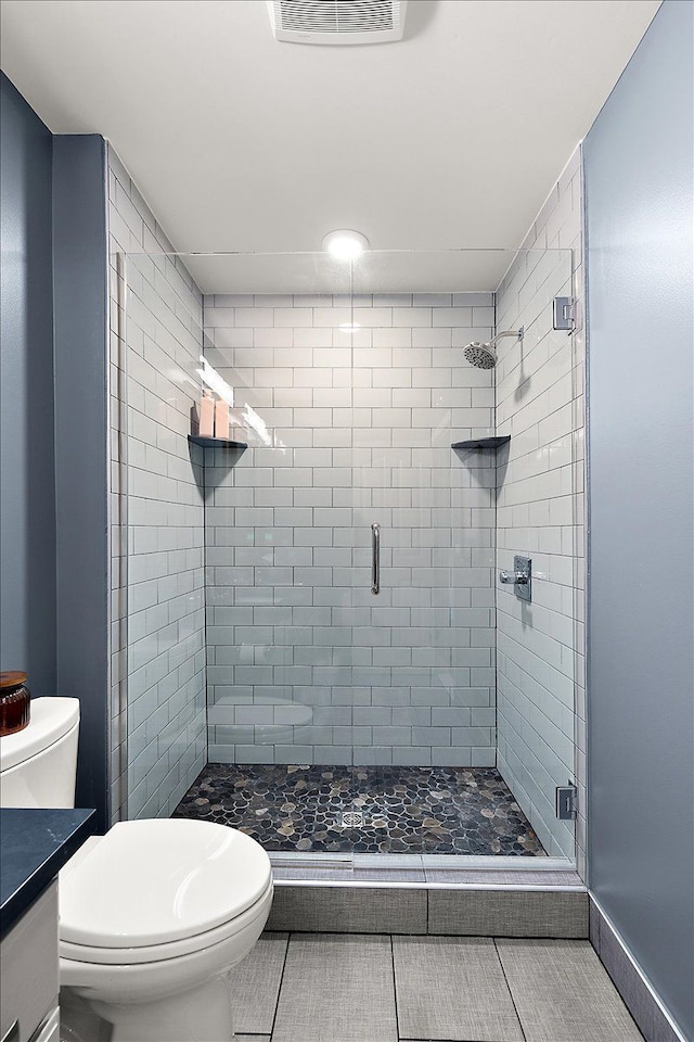 bathroom with tile patterned floors, vanity, toilet, and walk in shower