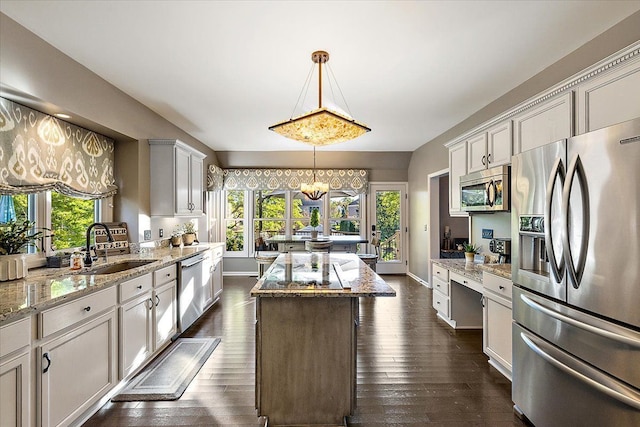 kitchen with a center island, dark wood-type flooring, a wealth of natural light, stainless steel appliances, and a sink