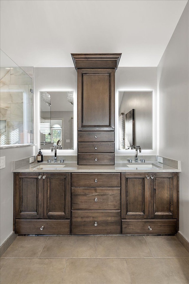 bathroom featuring double vanity, tile patterned flooring, tiled shower, and a sink