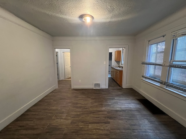 unfurnished bedroom featuring ensuite bath, dark hardwood / wood-style flooring, a textured ceiling, and sink