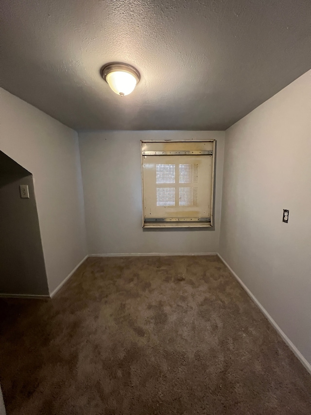 empty room with a textured ceiling and dark carpet