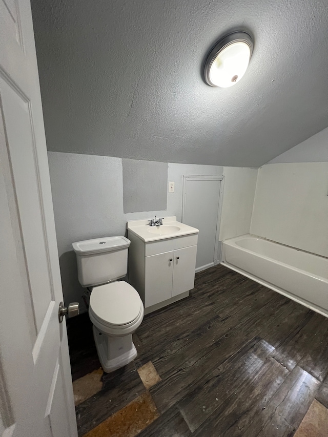 bathroom with vanity, a bath, toilet, a textured ceiling, and wood-type flooring