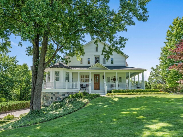 country-style home featuring covered porch and a front yard