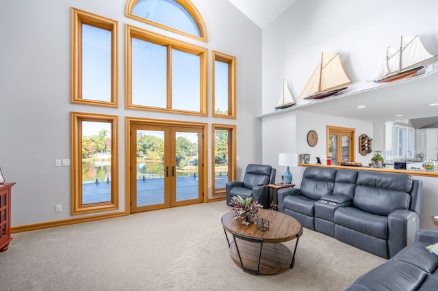 carpeted living room with french doors and high vaulted ceiling