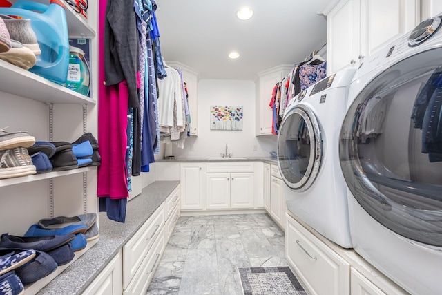 clothes washing area featuring washer and dryer, cabinets, and sink