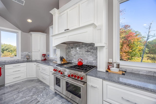 kitchen featuring lofted ceiling, decorative backsplash, white cabinetry, and range with two ovens