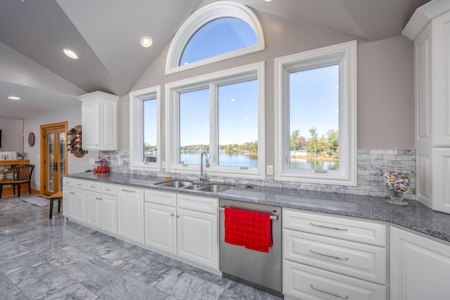 kitchen featuring decorative backsplash, vaulted ceiling, sink, a water view, and white cabinets