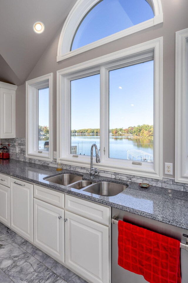 kitchen with dishwasher, a water view, sink, vaulted ceiling, and white cabinetry