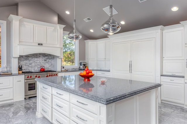 kitchen with pendant lighting, dark stone counters, vaulted ceiling, high end stove, and a kitchen island