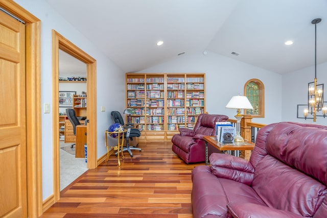 living room featuring hardwood / wood-style flooring, vaulted ceiling, and a notable chandelier