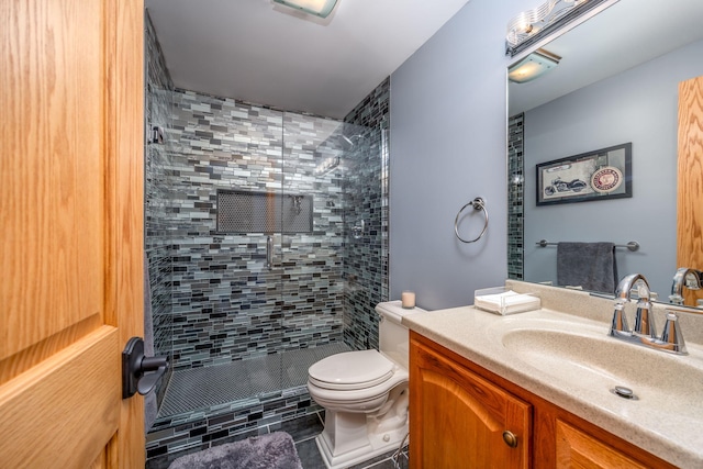 bathroom with tiled shower, tile patterned floors, vanity, and toilet