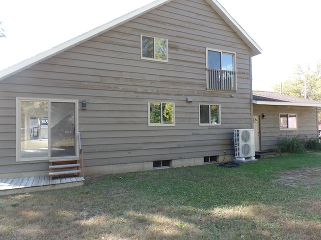 rear view of property featuring a lawn and ac unit