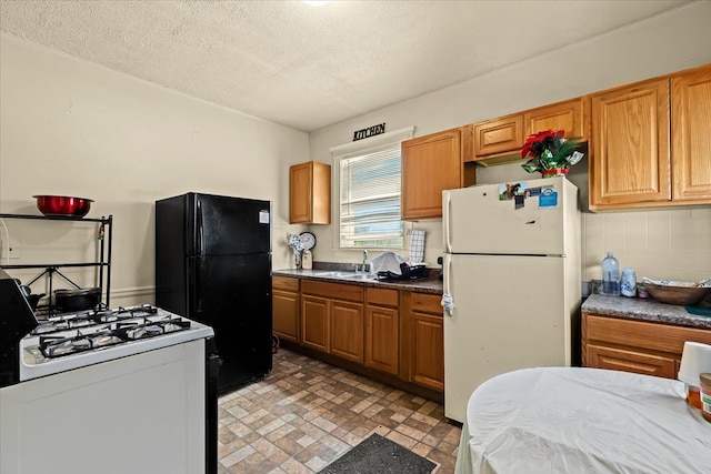 kitchen with a textured ceiling, sink, and white appliances