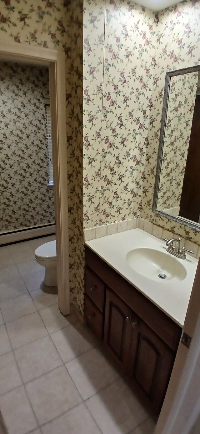 bathroom with toilet, vanity, a baseboard radiator, and tile patterned floors