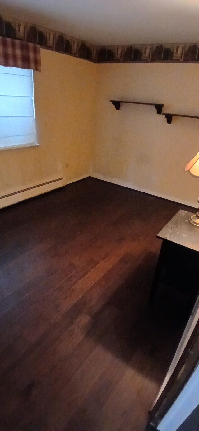 empty room with baseboard heating and hardwood / wood-style floors