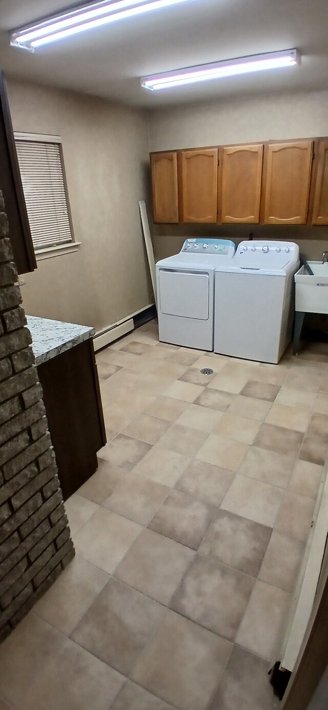 washroom featuring cabinets, a baseboard radiator, washer and clothes dryer, and sink