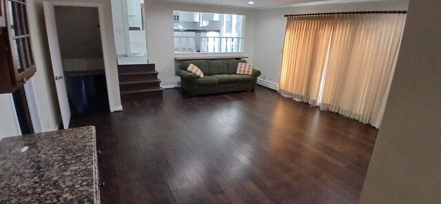 unfurnished living room with baseboard heating and dark wood-type flooring