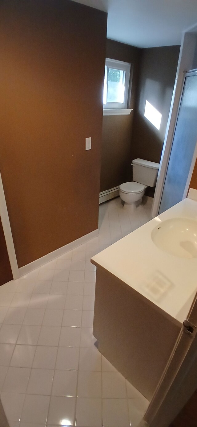 bathroom with tile patterned floors, toilet, baseboard heating, and sink