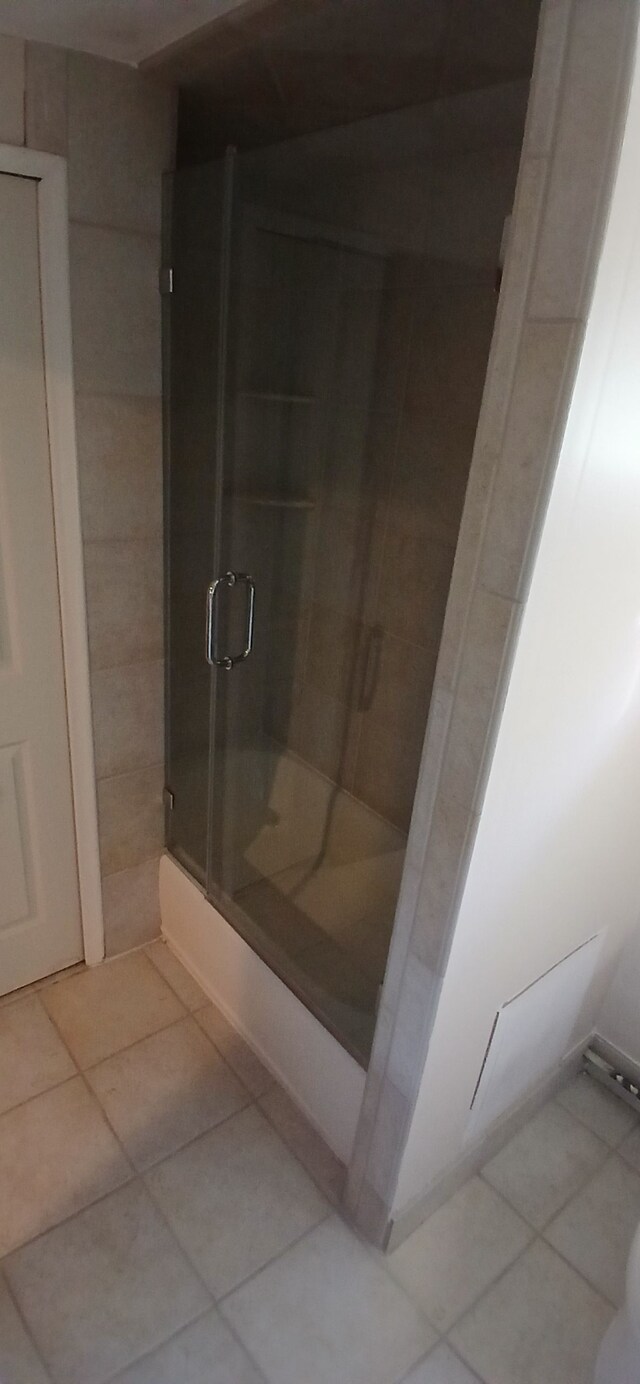 bathroom with tile patterned floors and bath / shower combo with glass door