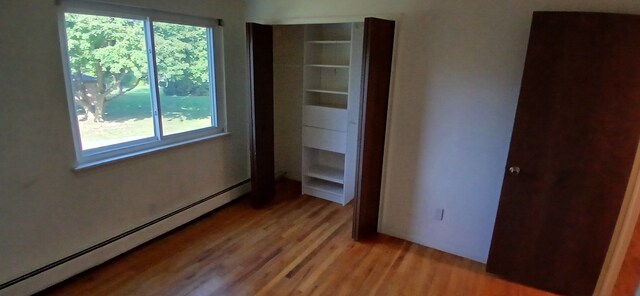 unfurnished bedroom with light wood-type flooring and a baseboard radiator