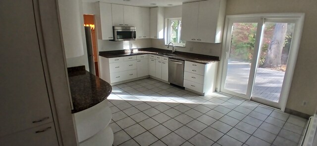 kitchen featuring sink, white cabinets, light tile patterned floors, and appliances with stainless steel finishes