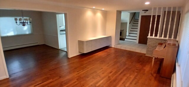 unfurnished room with dark wood-type flooring, a baseboard radiator, and an inviting chandelier