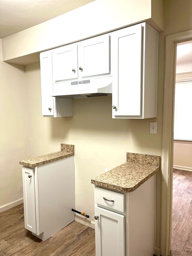 kitchen featuring light stone countertops, white cabinets, and hardwood / wood-style flooring