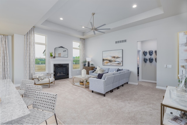 carpeted living room featuring a tray ceiling and ceiling fan