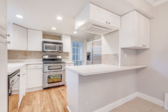 kitchen with stainless steel appliances, kitchen peninsula, light wood-type flooring, white cabinets, and ornamental molding