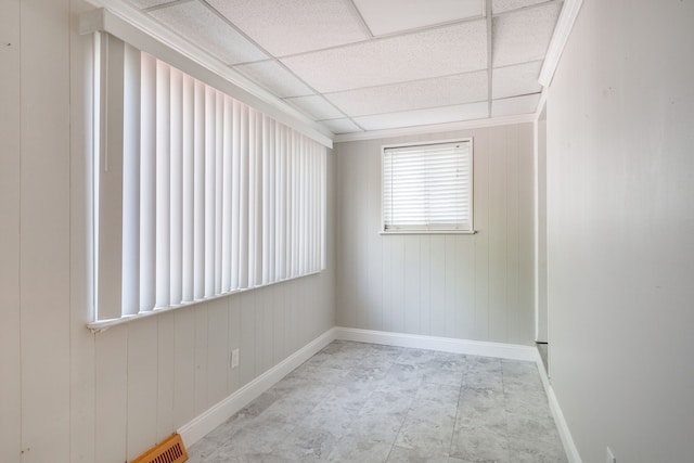 empty room with a paneled ceiling and wood walls