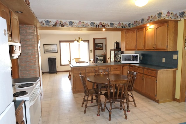 kitchen with white appliances, hanging light fixtures, ornate columns, a notable chandelier, and kitchen peninsula