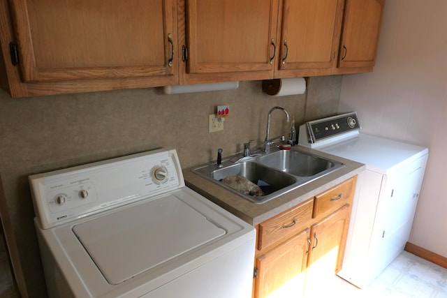 clothes washing area with washing machine and dryer, sink, and cabinets