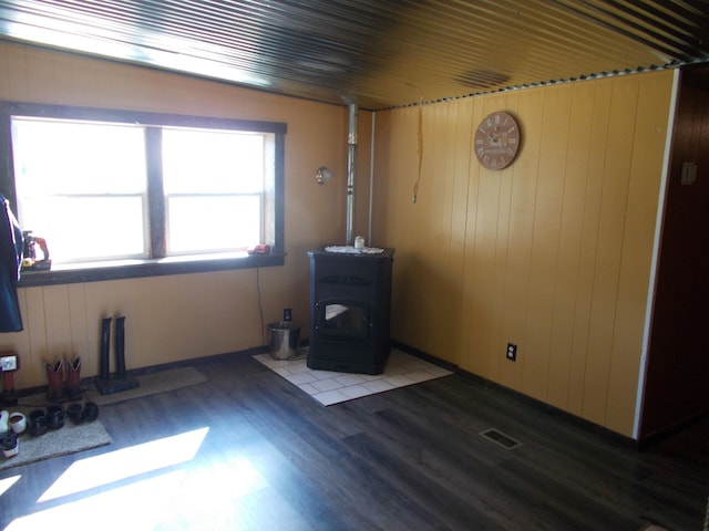 spare room featuring dark hardwood / wood-style flooring, a wood stove, and wooden walls