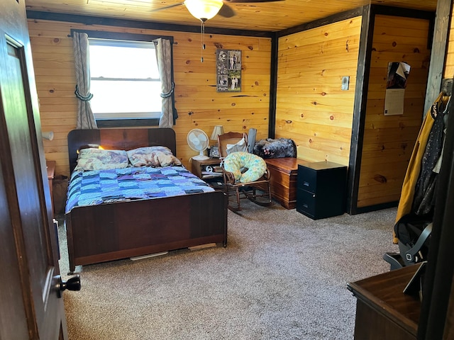 carpeted bedroom featuring wooden walls, ceiling fan, and wood ceiling