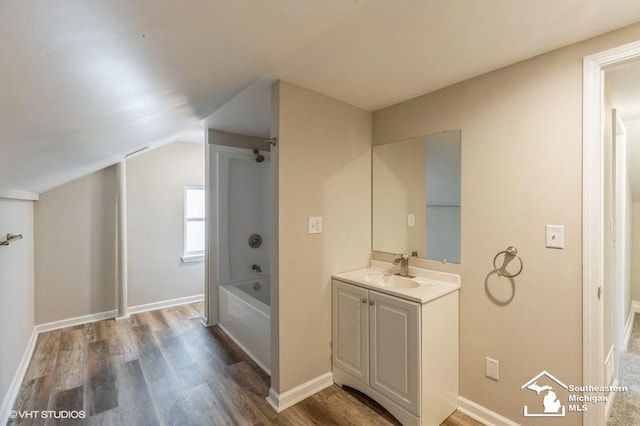 bathroom with lofted ceiling, wood-type flooring, vanity, and bathtub / shower combination