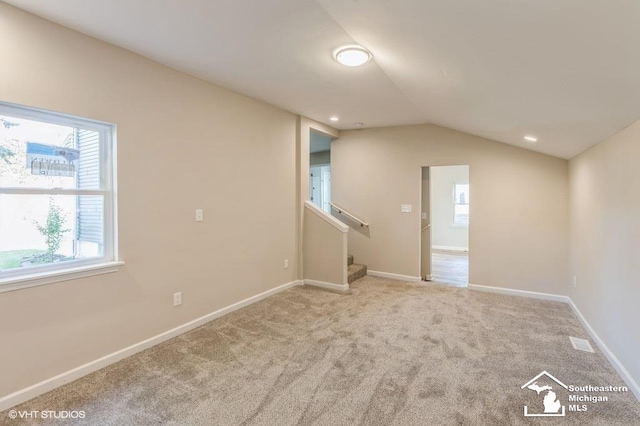 additional living space with light carpet, a healthy amount of sunlight, and vaulted ceiling