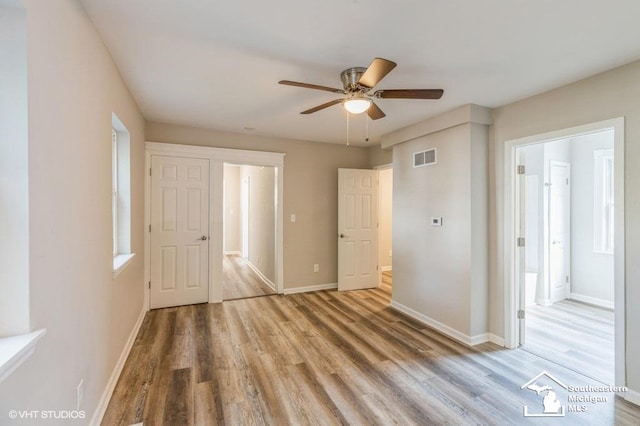 unfurnished bedroom featuring connected bathroom, hardwood / wood-style flooring, and ceiling fan