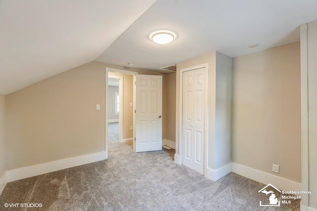 bonus room with light colored carpet and vaulted ceiling