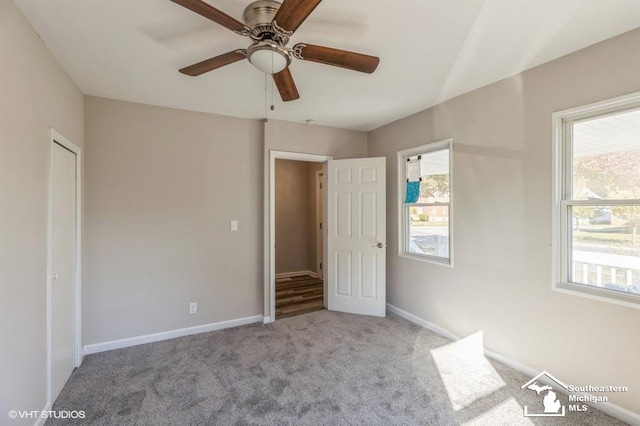 unfurnished bedroom with a closet, light colored carpet, multiple windows, and ceiling fan