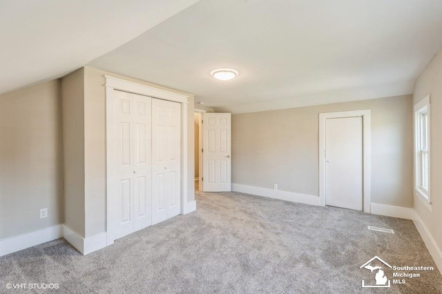 unfurnished bedroom with light carpet and a closet