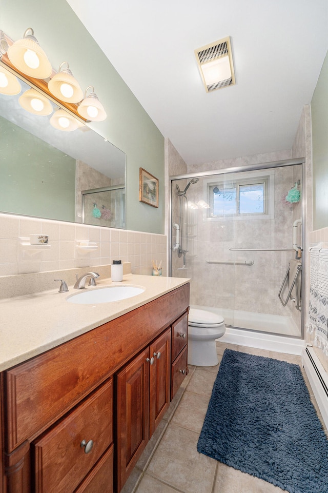 bathroom featuring vanity, tile patterned flooring, toilet, tile walls, and a baseboard radiator